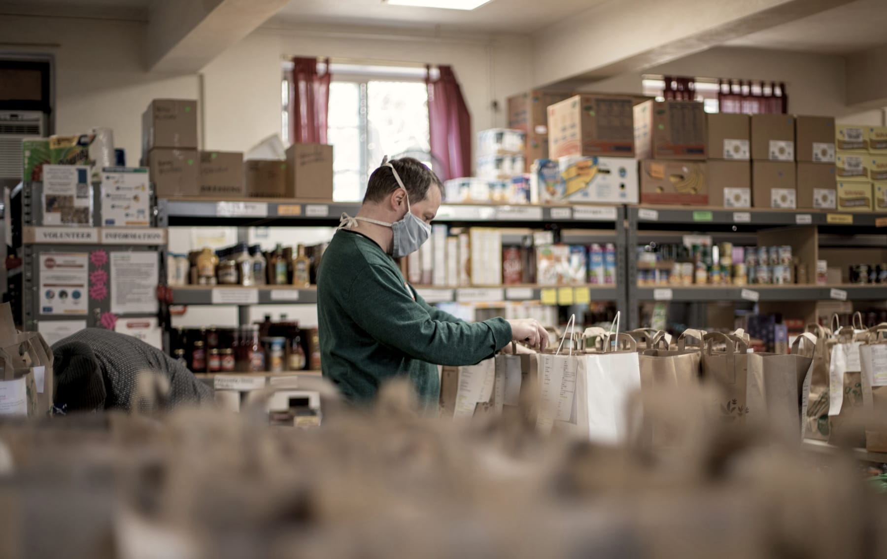 A volunteer packs grocery bags in a food pantry